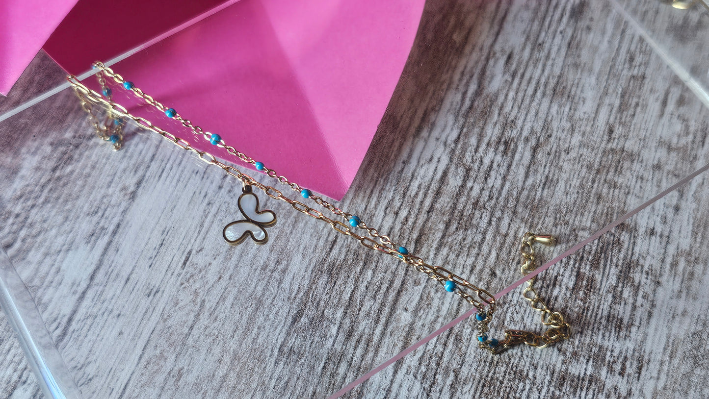 Chevillière double rang dorée avec perles bleues et pendentif papillon nacré